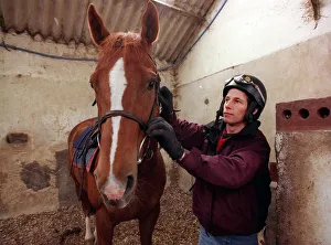 Jockey John McAuley cleaning bridle of the horse Serious Hurry in stables, June 1988