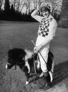 Jockey Simon Whitaker in his racing silks stands astride 21 inch high Bluebell