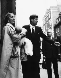 John F Kennedy after the christening of Anna Christina Radziwill who is held by godmother