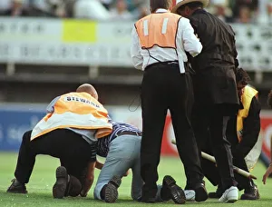 John Holder umpire is helped by steward after he was knocked to the ground by a fan