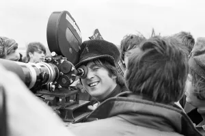 John Lennon of the Beatles pop group, looking through the lens of a camera during
