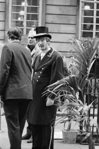 John Lennon plays the part of a club commissionaire in this filming picture from 27th