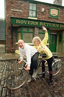Julie Goodyear and Roy Barraclough pictured on a tandem bike on the set of Coronation