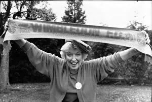 Final Prints: June Whitfield, actress and Wimbledon Football Club supporter holds the teams scarf aloft