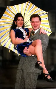 Kathryn Dixon being lifted by John Leslie holding yellow and white striped umbrella