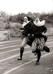 Kevin Moran and David Cannon dressed as Nuns hold on to their skirts in the 100m dash