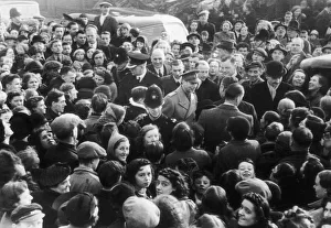 King George VI surrounded by a crowd of enthusiastic people welcoming him to the bomb