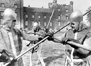 Knaves in jerkins and steel helmets battle with quarter staffs during the jousting