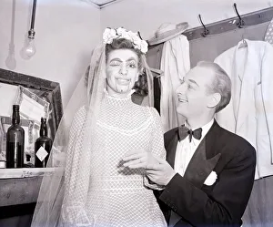 A lady wears make-up to make her look like a ventriloquists dummy sits on a mans lap in a
