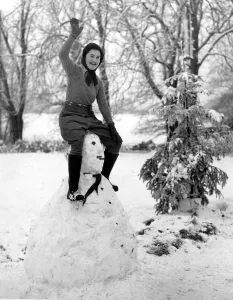 00095 Prints: A land army girl in Sussex sitting on top of her Hitler snowman during the Second World