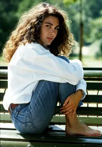 Laurence Ashley a French actress sitting sideways on a park bench with her feet up