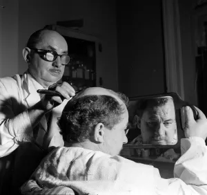 Barber Prints: Leo McKern looks at his reflection in a mirror after getting a special hair do for a