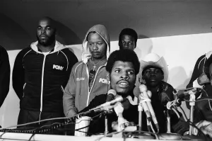 Microphones Prints: Leon Spinks speaking at a press conference (flanked by body guard Mr T left