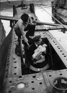 00035 Prints: Lieutenant Commander HRB Newton entering in the submarine torpedo space with his son Max