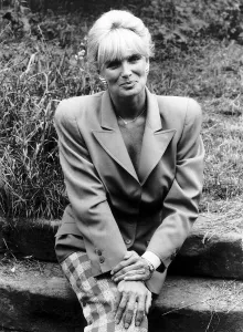 Screen Prints: Linda Evans American Actress of Dynasty fame sitting on concrete steps in garden