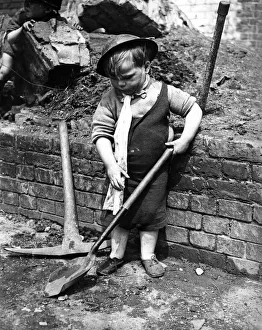 01443 Prints: A little boy pays with a shovel following air raid attacks in England. Circa 1941