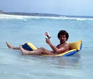 Book Prints: Liverpool footballer Graeme Souness relaxes reading a book on an inflatable bed