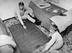 01127 Prints: Liverpool forward Roger Hunt at home playing subbuteo with his son