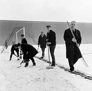 Liverpool manager Bill Shankly helps to clear the snow from the goal line on the Anfield
