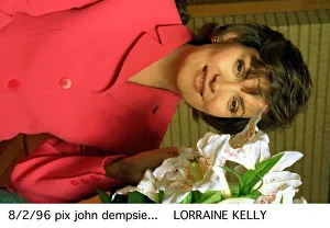 Lorraine Kelly TV presenter wearing a pink suit poses with some flowers