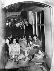 00862 Prints: Making sandbags in the shelter - Women are making and men filling sandbags in