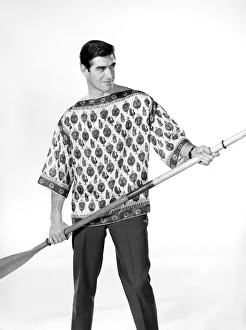Male model Peter Christian wearing silk shirt seen here holding a oar. Circa 1964