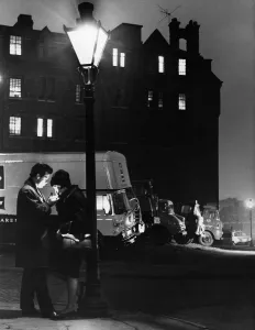 Cigarette Prints: A man lighting a cigarette for a woman, standing under a street lamp at night
