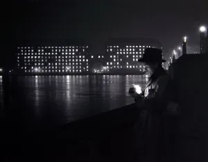 Espionage Prints: A man lights a cigarette on the Thames embankment in London Circa 1955 people