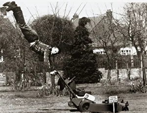 Housework Prints: A man mowing his lawn with doing a hand stand on the handles of an electrical lawn mower
