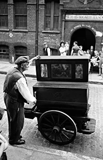 Tower Hamlets Prints: A man plays the barrel organ outside Hogarth Houses in Whitechapel, East London