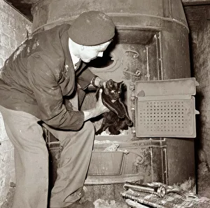 A man rescuing a cat which had become stuck inside an oven Circa October 1956