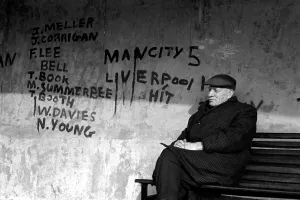 Vandalism Prints: Man sitting on a bench at a bus shelter covered with graffiti after a football match