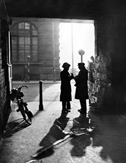 A man talking to a newspaper seller under the covered entrance to Leather Lane