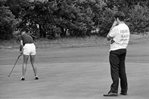A man watches a woman playing golf during the Colgate European Women
