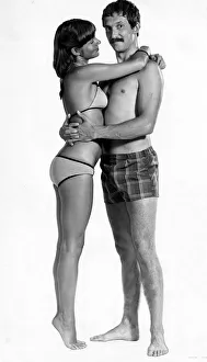 A man wearing checked shorts embracing a woman wearing a bikini August 1976
