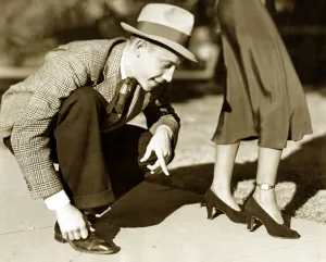 Admiration Prints: A Man wearing a tweed jacket, trousers and a trilby hat bends over to check the time on a