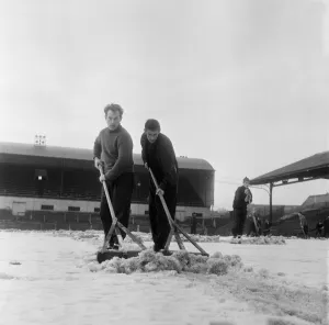 Manager Joe Harvey and players, clear snow from pitch at St James Park