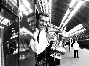 Manchester United captain Noel Cantwell leaning from the train with the FA cup trophy