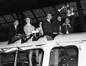 Manchester United captain Noel Cantwell (right) proudly holds aloft the FA Cup trophy to
