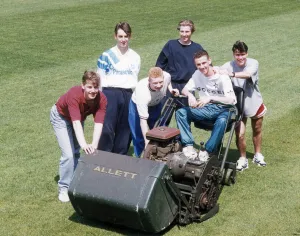 Only Young Men Prints: Manchester United youth team players surrounding a lawnmower on the pitch at The Cliff