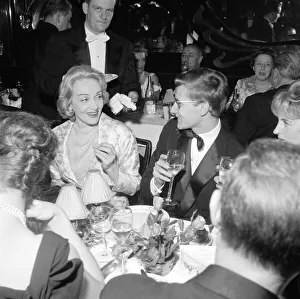 1950s Fashion Prints: Marlene Dietrich with Yves St. Laurant in Paris sitting at dinner table in a restaurant