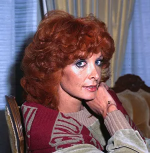 Marti Caine comedienne wearing brown red jumper hand at chin