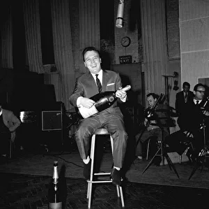 Matt Monro sitting on stool in recording studio holding bottle of champagne