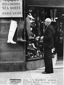 May 1950. Alderman TR Broadbent looking at a shop display of boots outside a shop by