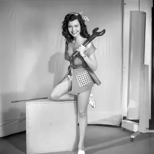 Tool Prints: The Mechanic: Woman in fancy dress holding large spanner. 1959 E40-003