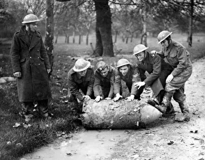 Members of a army bomb disposal squad rolling a unexploded German bomb through a London