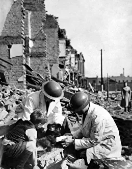 00113 Prints: Members of a rescue squad giving treatment to a wounded dog who survived last nights air