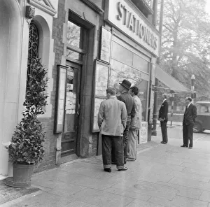 Men looking at local classified and personal adverts on notice board outside shop