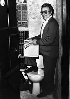 Images Dated 18th March 1976: Michael Bentine, in the toilet at his home, browsing through a volume of Encyclopedia