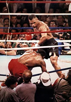Mike Tyson Heavyweight Boxer stands over the hunched figure of Frank Bruno after knocking